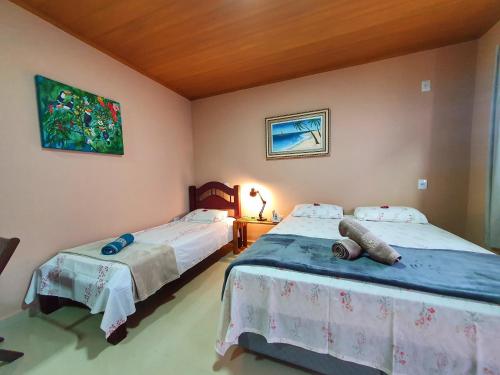 a bedroom with two beds and a painting on the wall at Pássaros do Cerrado Suítes in Alto Paraíso de Goiás