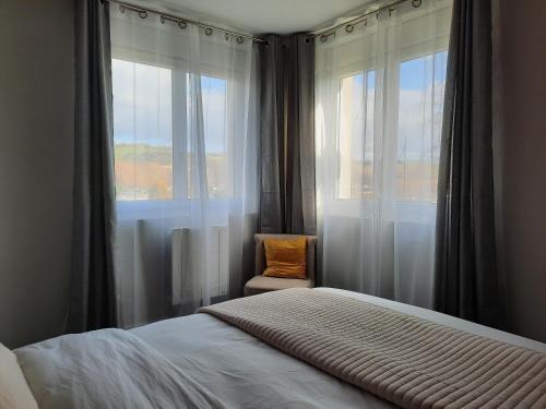 una camera con letto, sedia e finestre di Résidence Privée entre Varengeville/mer & Dieppe a Hautot-sur-Mer