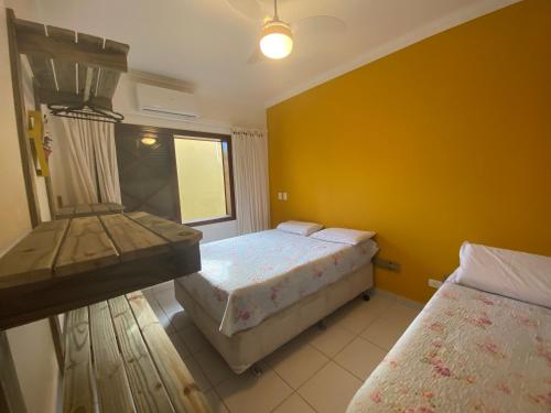 1 dormitorio con 2 camas y pared amarilla en Flat 1 Dorm. Maresias Praia&Lazer& Ar&Piscina F3 en São Sebastião