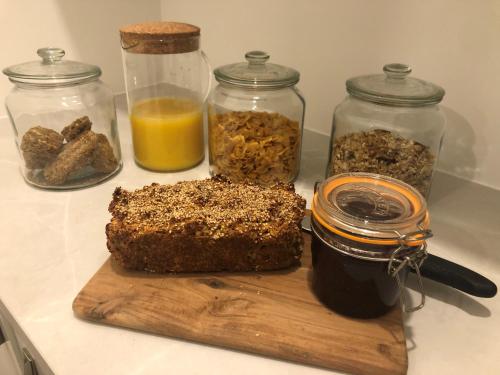 a cutting board with a loaf of bread and jars of food at Kearney's Cottage B&B in Killenard