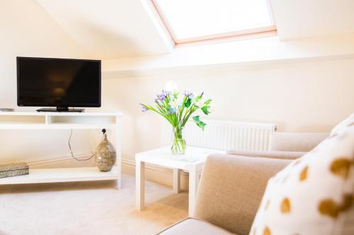 a living room with a vase of flowers on a table at Higher Weddicott Barn Holiday Cottage - Self Catering in Chagford