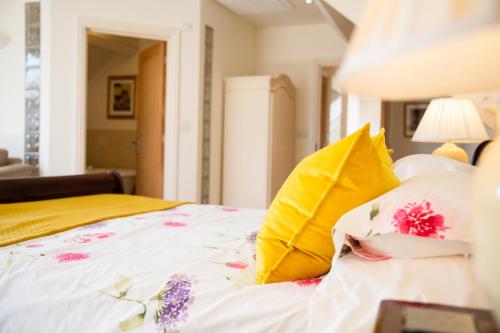 a bed with yellow and pink pillows on it at Higher Weddicott Barn Holiday Cottage - Self Catering in Chagford