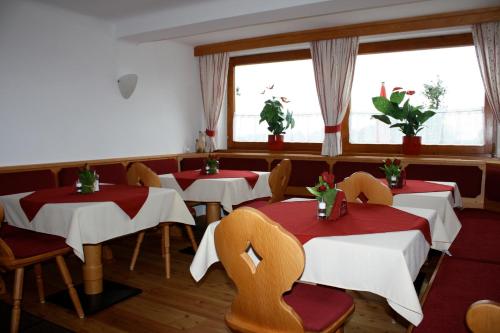 ein Restaurant mit Tischen, Stühlen und Fenstern in der Unterkunft Pension Haus Maria in Ramsau am Dachstein