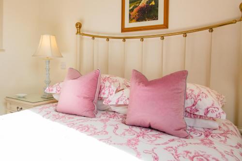 a bed with pink pillows on top of it at Higher Weddicott Barn Holiday Cottage - Self Catering in Chagford