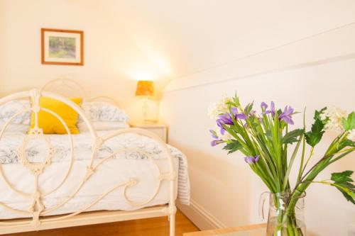 a bedroom with a white bed and flowers in a vase at Higher Weddicott Barn Holiday Cottage - Self Catering in Chagford