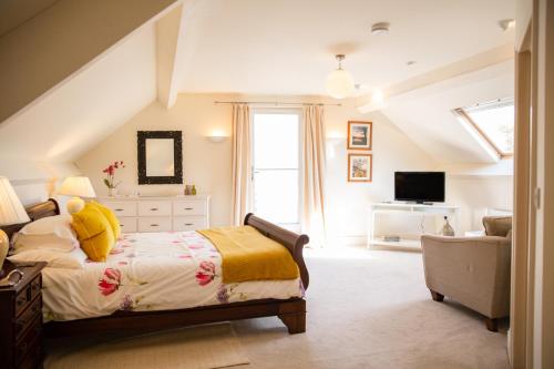 a bedroom with a bed and a couch and a television at Higher Weddicott Barn Holiday Cottage - Self Catering in Chagford