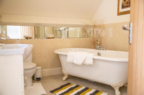 a bathroom with a tub and a toilet and a sink at Higher Weddicott Barn Holiday Cottage - Self Catering in Chagford
