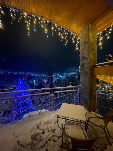 a snowy balcony with a table and chairs and lights at Sadyba u Halyny in Bukovel