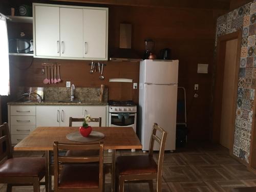 uma cozinha com uma mesa e um frigorífico branco em Chalé Gregório em Imbituba