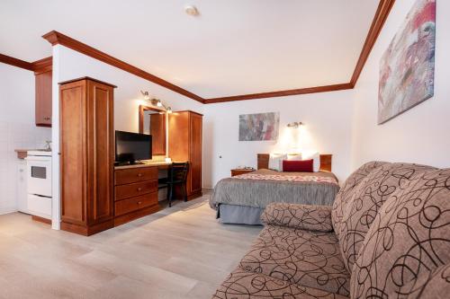 a hotel room with a bed and a desk and a television at Hotel Plante in Gaspé