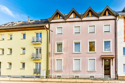 a pink building in front of two yellow buildings at A-Apartment in Bad Säckingen