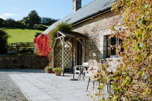 a stone building with a table and chairs in front of it at Higher Weddicott Barn Holiday Cottage - Self Catering in Chagford