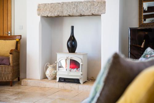 a white fireplace in a living room with a vase at Higher Weddicott Barn Holiday Cottage - Self Catering in Chagford