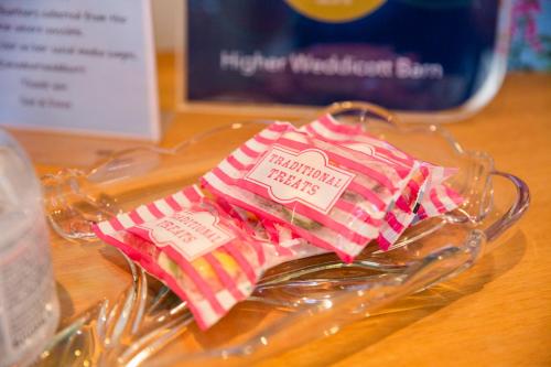 a pair of pink and white striped napkins in a glass container at Higher Weddicott Barn Holiday Cottage - Self Catering in Chagford