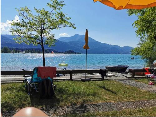 a chair and an umbrella next to a lake at Apartmenthaus WALDHORN in St. Wolfgang