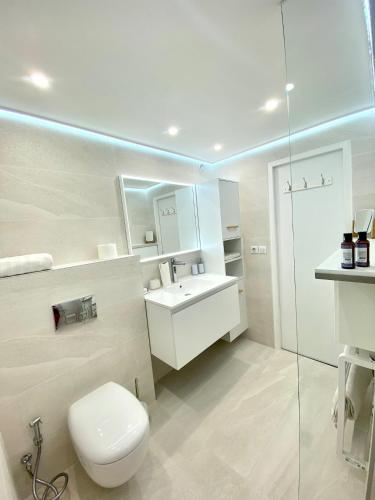 une salle de bain blanche avec des toilettes et un lavabo dans l'établissement Appartement Luxe - 3 pièces avec vue mer, piscine et tennis, à Nice