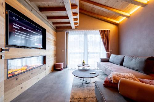 a living room with a couch and a flat screen tv at Chalet Imbosc'ché - 5 beautiful rooms in charming B&B in Livigno