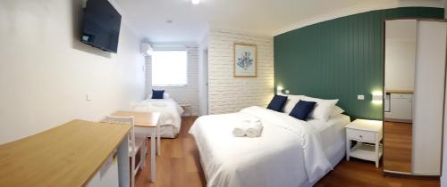 een slaapkamer met 2 bedden en een groene muur bij Bay House Motel in Bateau Bay