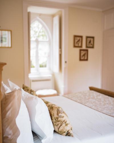a bedroom with a bed with white sheets and a window at Casa Holstein Quinta de Sao Sebastiao Sintra in Sintra