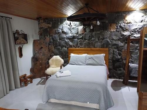 a bedroom with a bed and a stone wall at Aconchego da Serra Edícula in São Joaquim