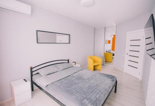 um quarto branco com uma cama e uma cadeira amarela em 094 ЖК Щасливий нова та сучасна квартира em Kiev