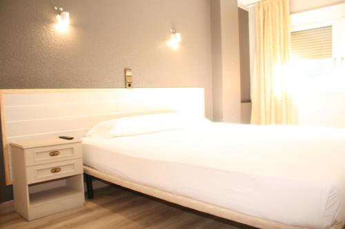 a bedroom with a large white bed and a night stand at HMC K-ena in Andorra la Vella
