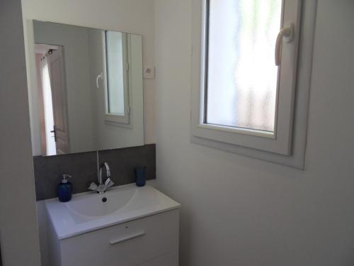 La salle de bains blanche est pourvue d'un lavabo et d'un miroir. dans l'établissement Appartement dans le verdon, à Allemagne-en-Provence