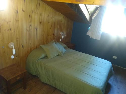 1 dormitorio con cama verde y pared de madera en Kalena 3 Playa Bonita DAT en San Carlos de Bariloche