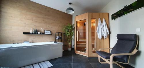 een badkamer met een bad en een stoel. bij La Perle du Semnoz in Annecy