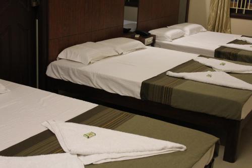 three beds in a hotel room with towels on them at Raj Residency Salem in Salem