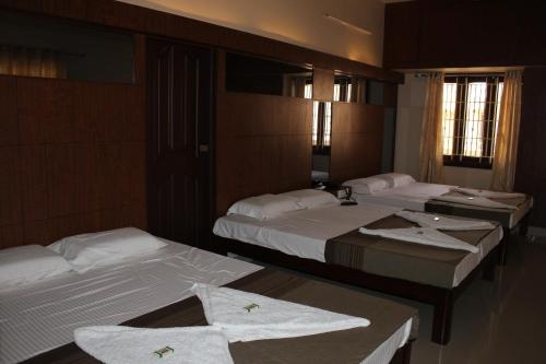a hotel room with three beds with towels on them at Raj Residency Salem in Salem
