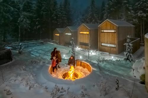 a group of people standing around a fire pit in the snow at Leśna Kąpiel in Karpacz