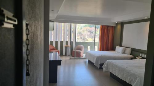 um quarto de hotel com duas camas e uma janela em Hotel Borda Cuernavaca em Cuernavaca