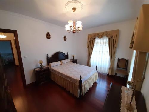a bedroom with a bed and a chandelier at Quintinha da Romana in Câmara de Lobos