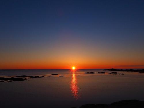 a sunset over the ocean with the sun reflecting in the water at Cozy cabin with stunning view in Alstad