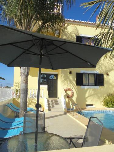 a table with an umbrella in front of a house at Apartamentos Paradise Fuseta in Fuzeta