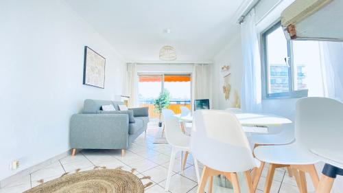 Il comprend un salon doté d'un mobilier blanc, d'une table et de chaises. dans l'établissement DELMAS - T3 VUE MER - Parc, Base loisirs, Bus Sophia Antipo, à Antibes