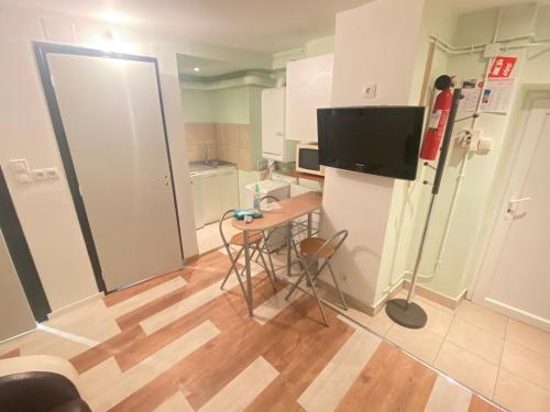 una pequeña cocina con mesa y TV. en Jolis studio meublé, en Angerville