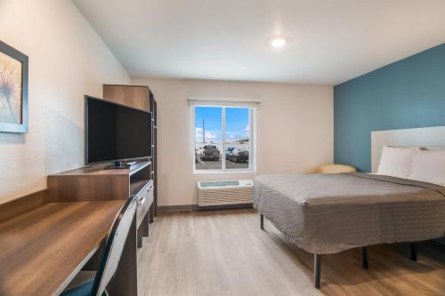a bedroom with a bed and a flat screen tv at WoodSpring Suites Colorado Springs North - Air Force Academy in Colorado Springs