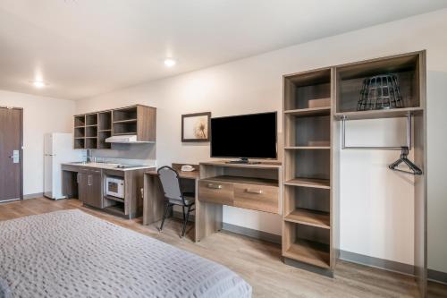 a bedroom with a desk with a television and a refrigerator at WoodSpring Suites Colorado Springs North - Air Force Academy in Colorado Springs