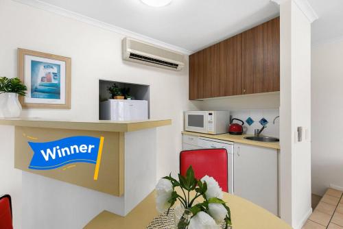a kitchen with a table and a counter with a microwave at Gorgeous Apartment in Luxurious Noosa Resort in Noosaville