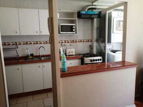 uma cozinha com armários brancos e uma bancada em Departamento, Playa Bellavista, Tomé em Tomé