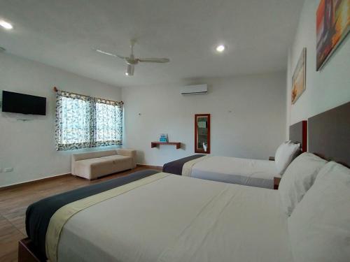 a hotel room with two beds and a television at José y Glendy Hotel in Progreso