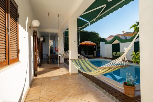 a hammock on the side of a house with a pool at Holiday villa in elite residential area of Faro in Faro