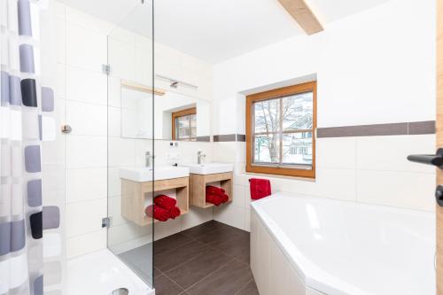 a white bathroom with a tub and a sink at Herzstück Appartements Zillertal in Kaltenbach