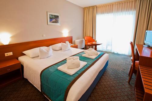 a hotel room with a bed with towels on it at Spa & Wellness Hotel Pinia in Malinska
