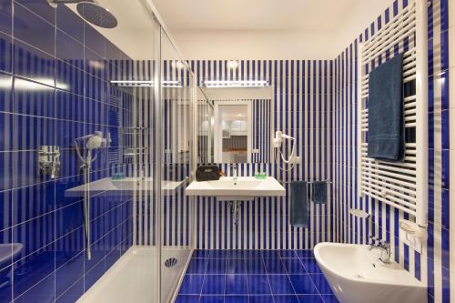 y baño con paredes de azulejos azules, lavabo y bañera. en Gorgeous apartment in the center: SORRENTO!, en Sorrento