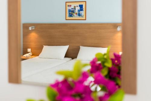 a bedroom with a bed with a mirror and pink flowers at HOTEL TINA FLORA in Kolimbia