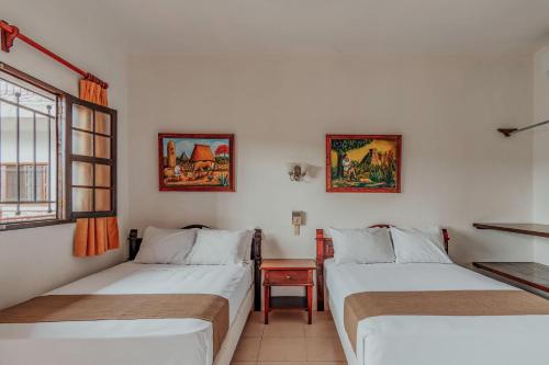 a room with two beds and a table and a window at Hotel Santa María Mérida in Mérida