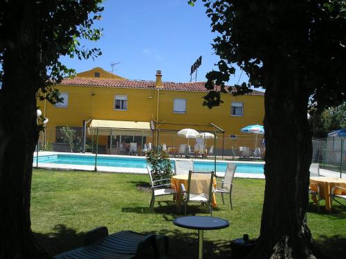 a yellow house with a table and chairs next to a pool at Hostal Restaurante Carolina in Pedrosillo el Ralo